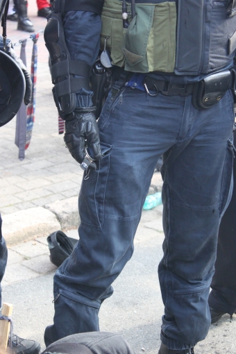 Polizist hält die abgerissene Uhr eines Demonstranten in der Hand